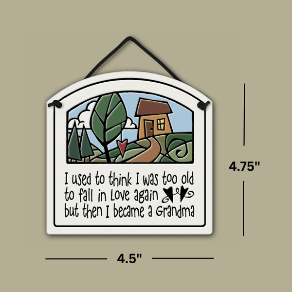 Ceramic wall tile with a cottage illustration and the quote ‘I used to think I was too old to fall in love again but then I became a Grandma,’ shown with dimensions 4.75 inches tall and 4.5 inches wide.