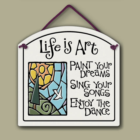 Ceramic wall tile with colorful sun and landscape illustration and the quote ‘Life is art—paint your dreams, sing your songs, enjoy the dance.’