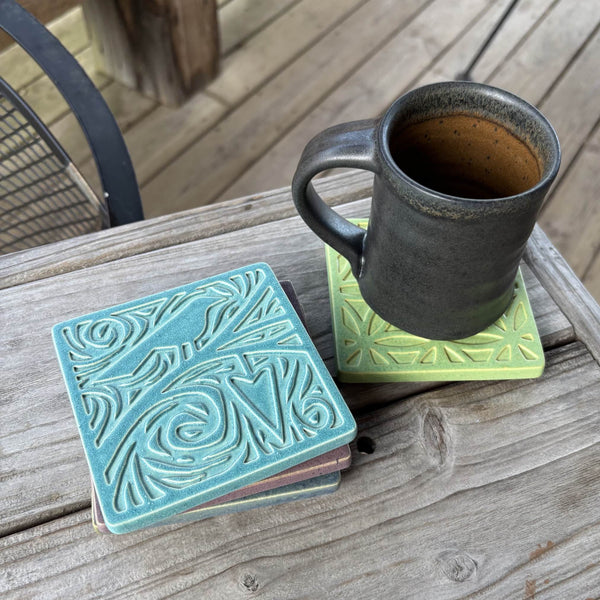 Handmade turquoise ceramic bird and heart coaster styled with a mug on a matching ceramic coaster by Macone Clay