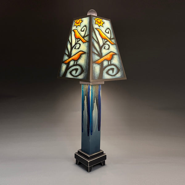 Birds in Tree handmade ceramic table lamp with straight blue extruded clay base, illuminated orange bird and sun shade by Michael Macone, made in Shell Lake Wisconsin