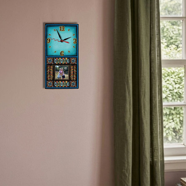 Blue Motif geometric picture frame wood wall clock hanging on a desert rose wall beside pampas grass and an olive linen curtain