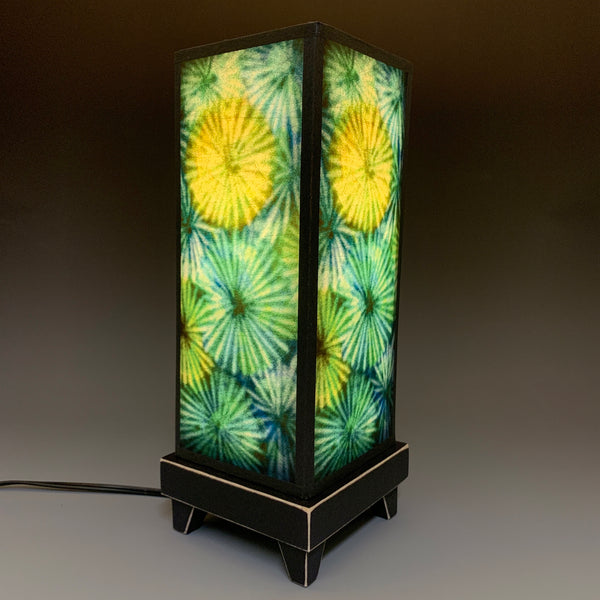 Carved Circles mood lamp lit and glowing with green and blue paper shade