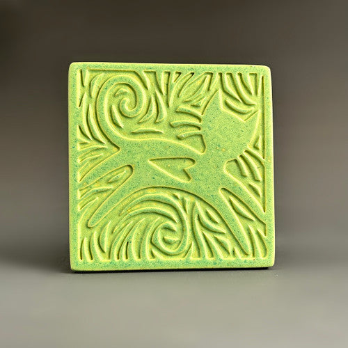 Handmade lime green ceramic cat coaster with leaping cat and swirling carved border by Macone Clay