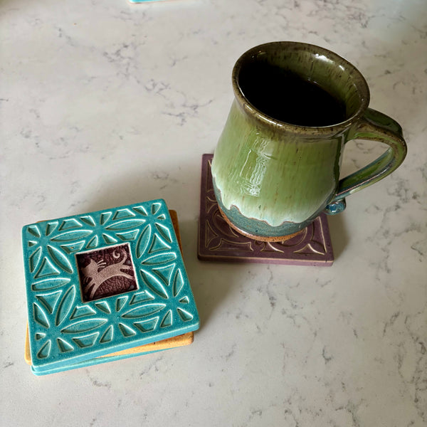 Handmade turquoise ceramic cat coaster styled with a mug on a matching ceramic coaster by Macone Clay