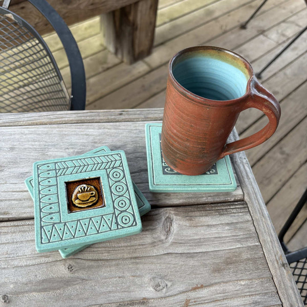 Handmade turquoise ceramic coffee cup coaster with crazed glass center styled with a mug on a matching ceramic coaster by Macone Clay