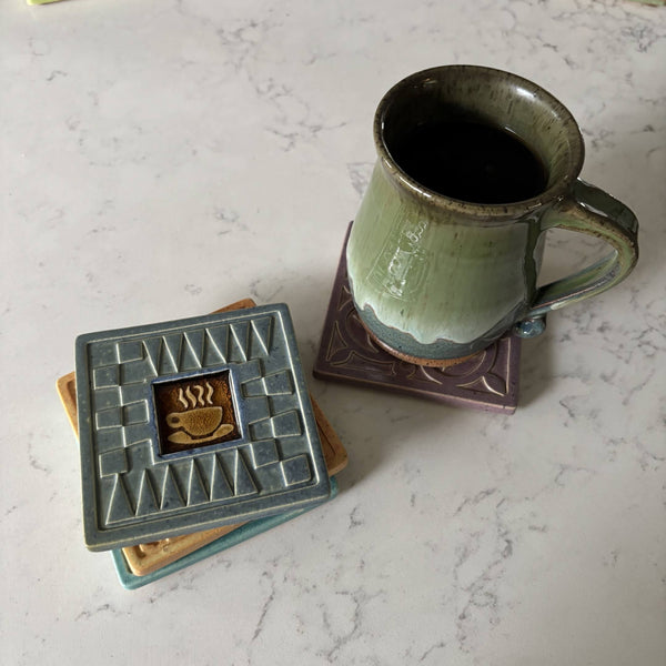 Handmade blue ceramic coffee cup coaster with crazed glass center styled with a mug on a matching ceramic coaster by Macone Clay