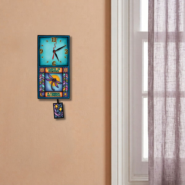 Dragonfly small pendulum wall clock hanging on a soft peach wall next to a window. 