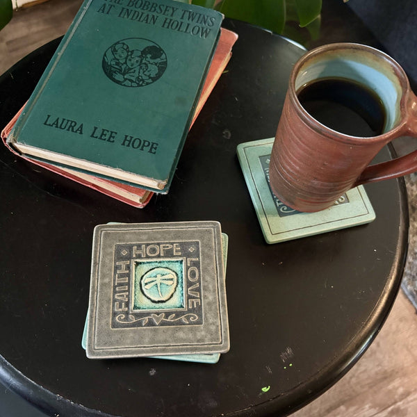 Handmade gray ceramic Faith Hope Love dragonfly coaster with crazed glass center styled with a mug on a matching ceramic coaster by Macone Clay