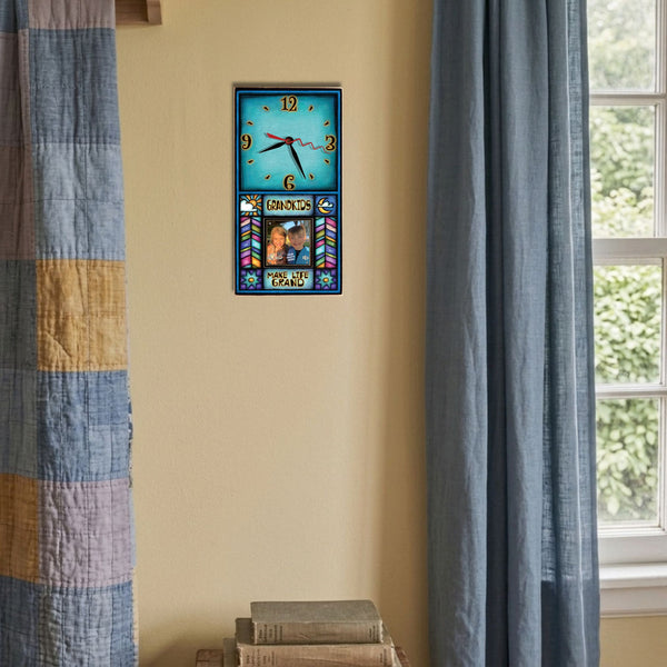 Grandkids Make Life Grand picture frame wood wall clock hanging on a wheat yellow wall beside a patchwork quilt and a dusty blue linen curtain