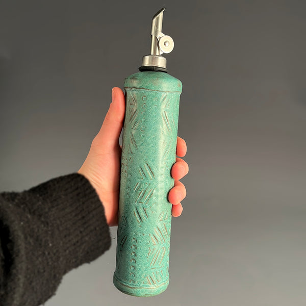 Hand holding handmade stoneware olive oil cruet with pour spout, ceramic oil dispenser by Macone Clay, functional kitchen accessory for cooking and gifting