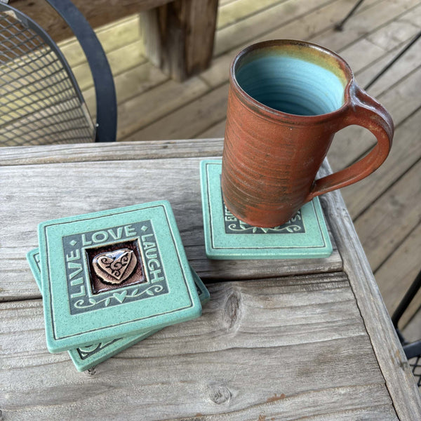 Handmade turquoise ceramic Live Love Laugh heart coaster with crazed glass center styled with a mug on a matching ceramic coaster by Macone Clay.