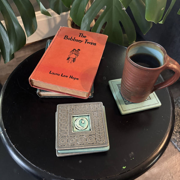 Handmade gray ceramic moon and star coaster with crazed glass center styled with a mug on a matching ceramic coaster by Macone Clay.