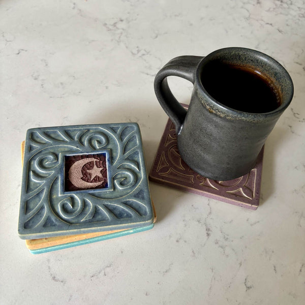 Handmade blue gray ceramic moon and star coaster with crazed glass center styled with a mug on a matching ceramic coaster by Macone Clay