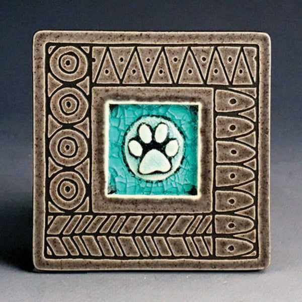 Handmade gray ceramic paw print coaster with crazed glass center and carved geometric border by Macone Clay