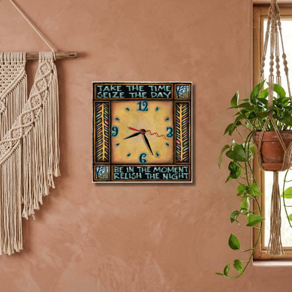 Seize the day square wood wall clock hanging on a slate blue wall in a cozy den beside a brass wall sconce and an olive linen curtain