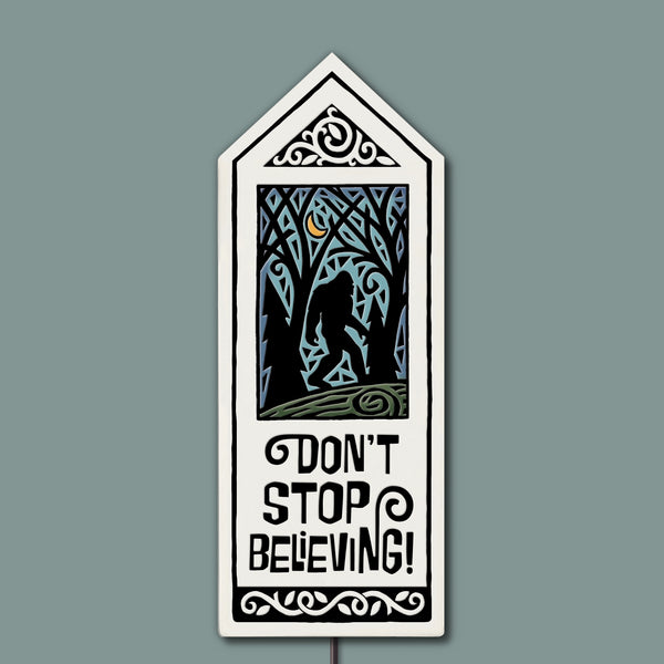 Hand-glazed ceramic garden tile stake with “Don’t Stop Believing” quote, featuring a moonlit forest silhouette design, outdoor weatherproof garden decor