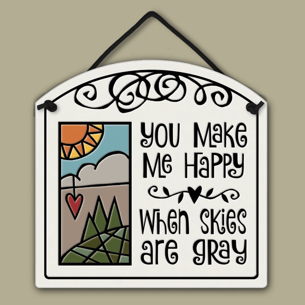 Spooner Creek small arch ceramic tile with quote “You make me happy when skies are gray,” featuring sun, clouds, hills, trees, and heart, handmade in Wisconsin