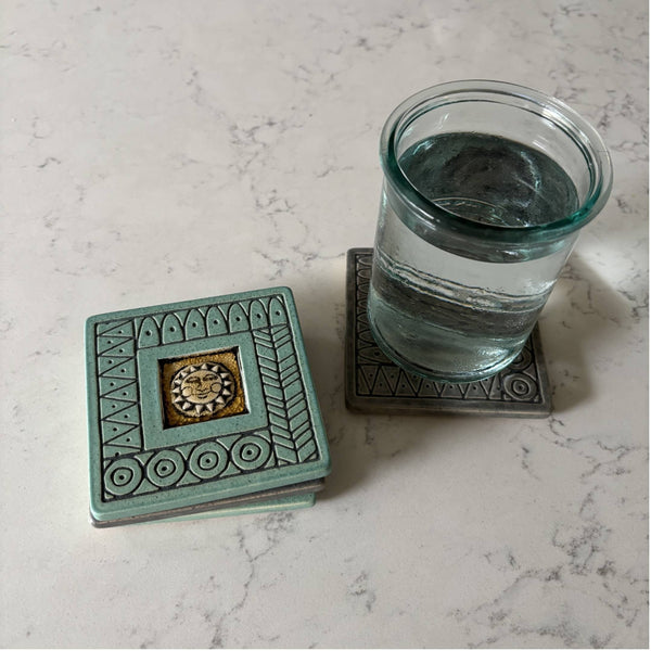 Handmade turquoise ceramic sun face coaster with crazed glass center styled with a mug on a matching ceramic coaster by Macone Clay