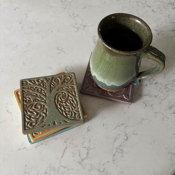 Handmade sage green ceramic tree coaster styled with a mug on a matching ceramic coaster by Macone Clay