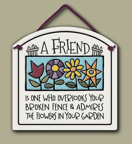 Ceramic wall tile with colorful flower illustration and the quote ‘A friend is one who overlooks your broken fence and admires the flowers in your garden.’