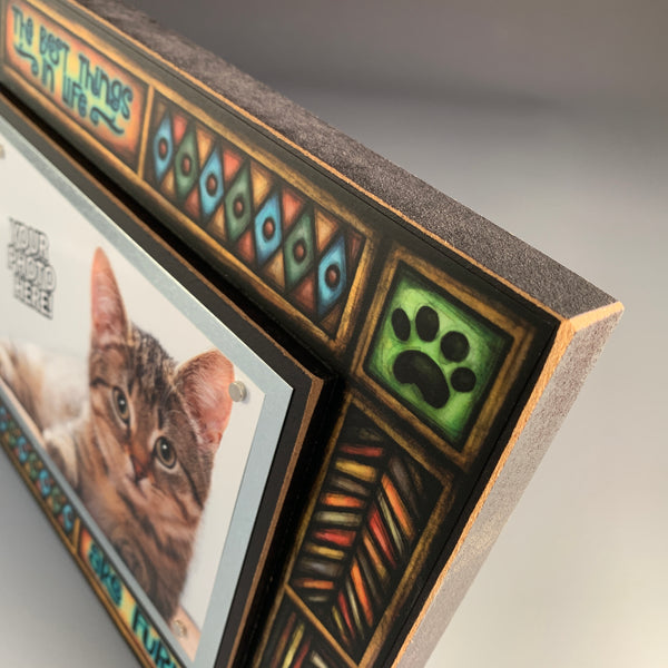 Corner detail of pet picture frame artwork showing colorful Michael Macone illustration and paw print design around quote.
