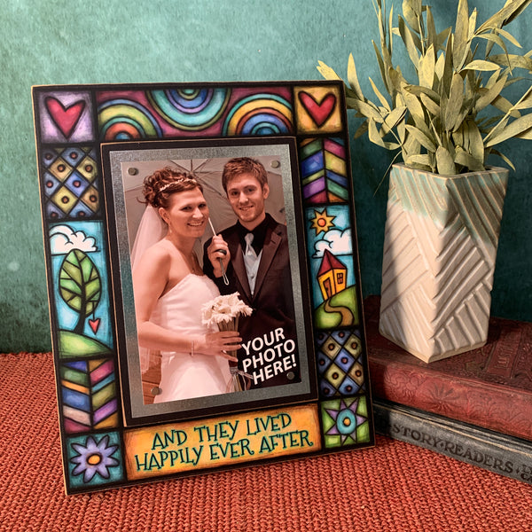 Wedding picture frame with the quote And they lived happily ever after displayed on shelf with colorful artwork and a centered 4x6 photo.
