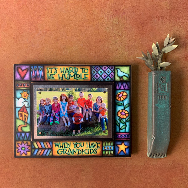 Grandkids picture frame wall display featuring the quote It’s hard to be humble when you have grandkids with colorful artwork surrounding a 4x6 photo.