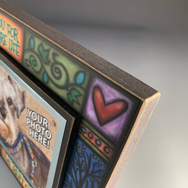 Corner detail of pet memorial picture frame artwork showing paw prints and colorful Michael Macone illustration around quote.