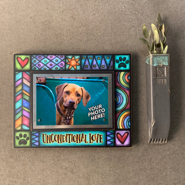 Pet picture frame with quote Unconditional Love hanging on a wall with colorful Michael Macone artwork and magnetic 4 x 6 pet photo display.