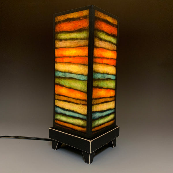 Rough Stripes mood lamp lit with room lights off, showing warm striped glow