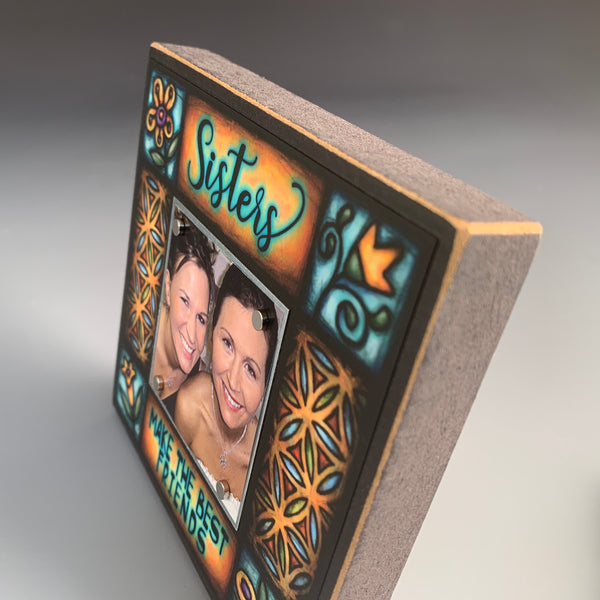Corner detail of Sisters Make the Best Friends picture frame featuring stained glass inspired floral artwork and warm golden tones by Michael Macone