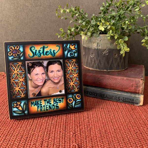 Sisters Make the Best Friends picture frame displayed on tabletop with Michael Macone artwork, small square wood frame with magnetic photo display, handmade in Shell Lake Wisconsin