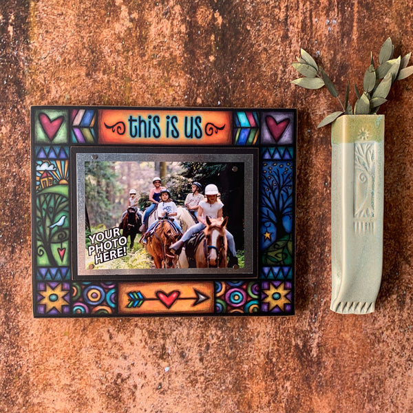 This Is Us 8x10 wood picture frame mounted on textured wall with 4x6 family photo and decorative vase nearby